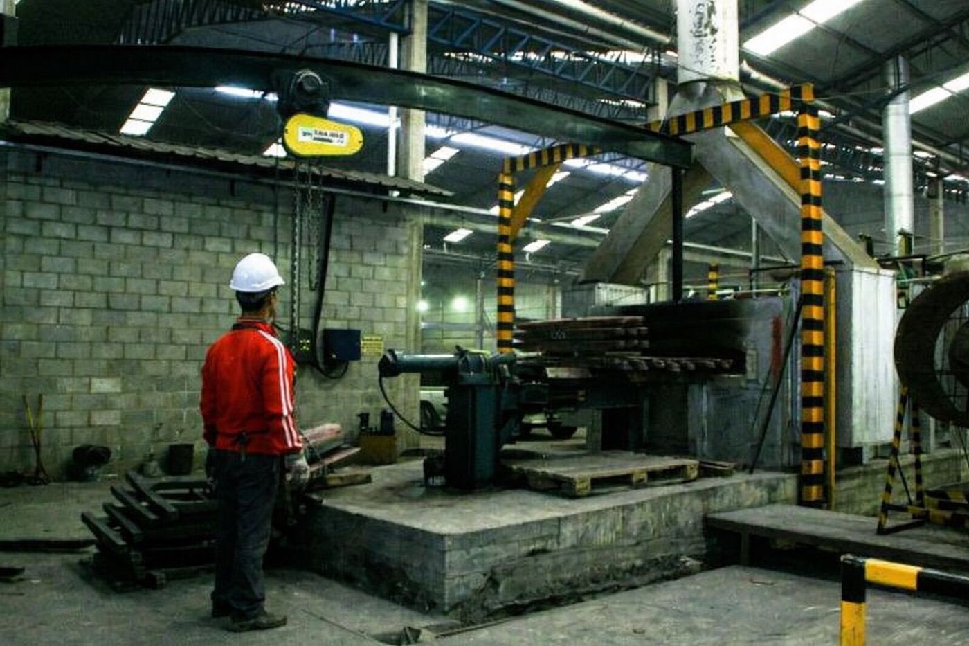 Operario supervisando operación con puente grúa en planta